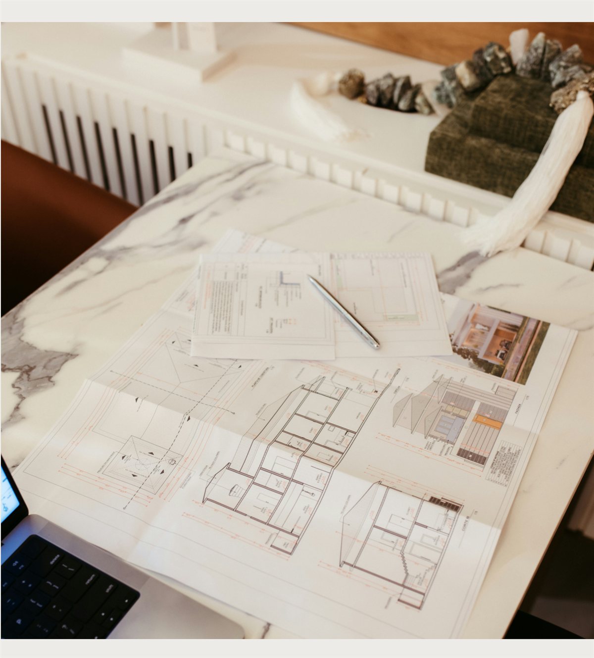 Property blueprints and floor plans spread across a marble table